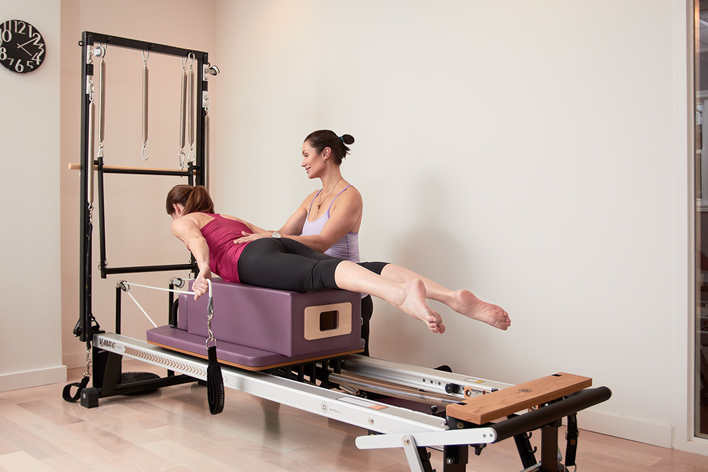 A woman is sitting on the back of a pilates machine