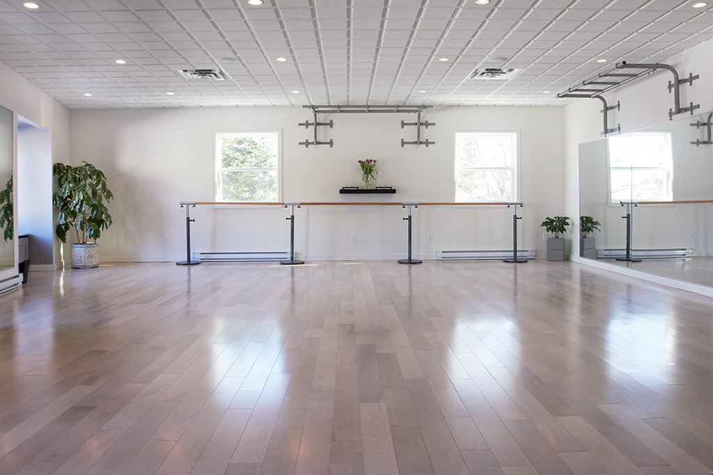 A dance studio with white walls and wooden floors.