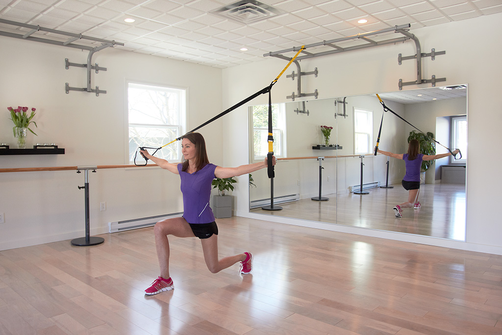 A woman is holding onto some poles in the gym